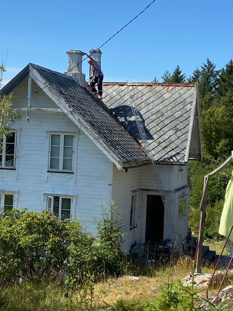 Arbeid på tak av tradisjonelt hvitt hus