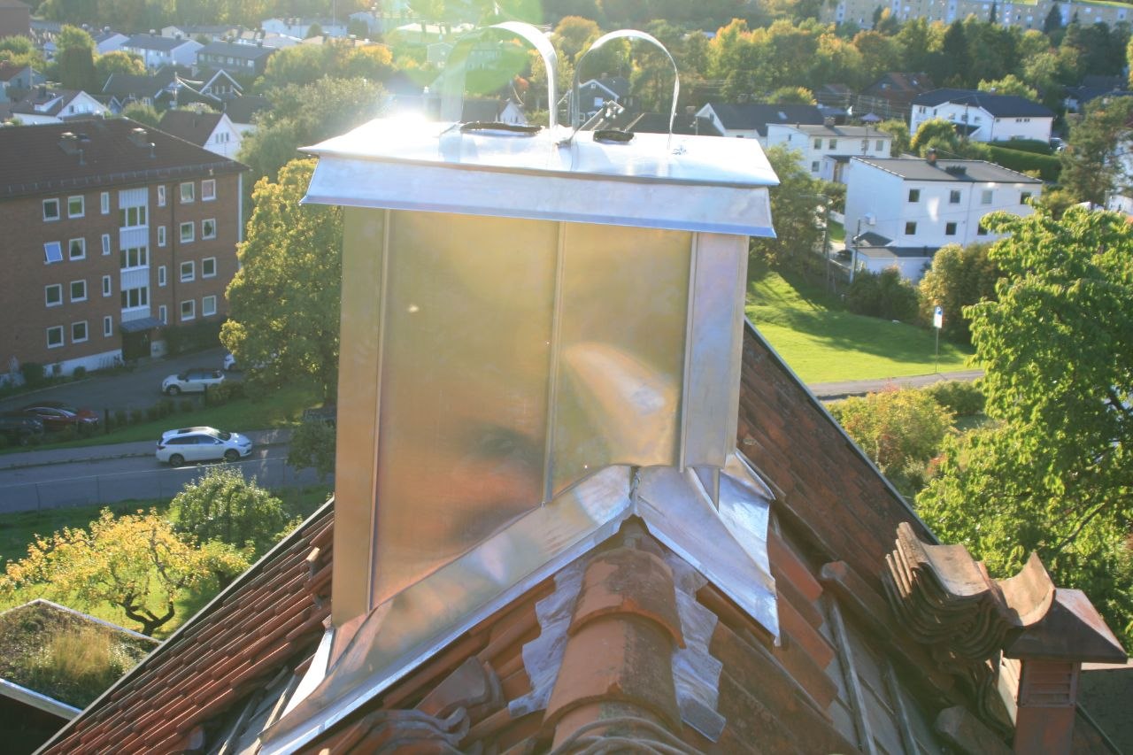 Zinkbeslag på pipe med utsikt over boligområde